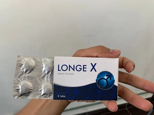 Mano sosteniendo la caja de Longe X Nueva Fórmula junto al blíster de tabletas